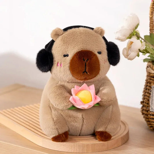 Plush capybara toy bear with headphones holding a flower on a wooden stand