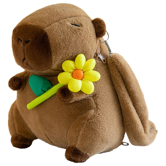 Brown plush capybara toy holding a yellow flower with a green stem on a white background