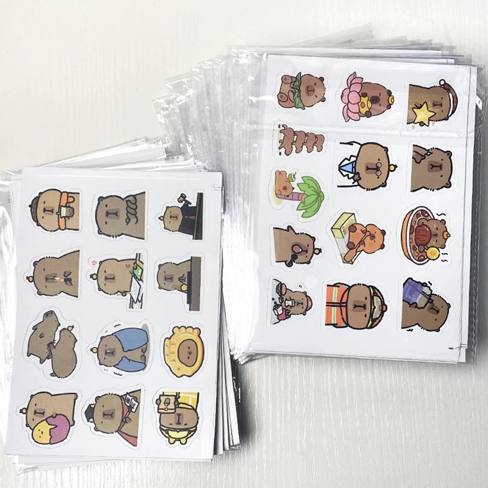 Sheets of cartoon capybara stickers with various accessories on a white surface.