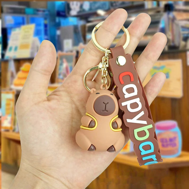 Capybara-shaped keychain with a hand holding it in a store setting