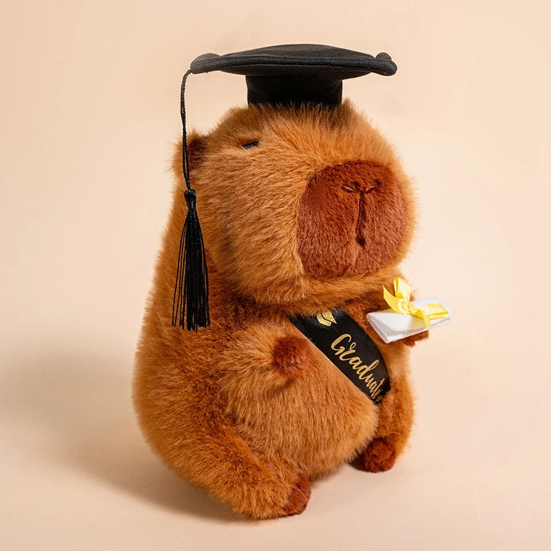 Plush capybara wearing a graduation cap and holding a diploma on a beige background