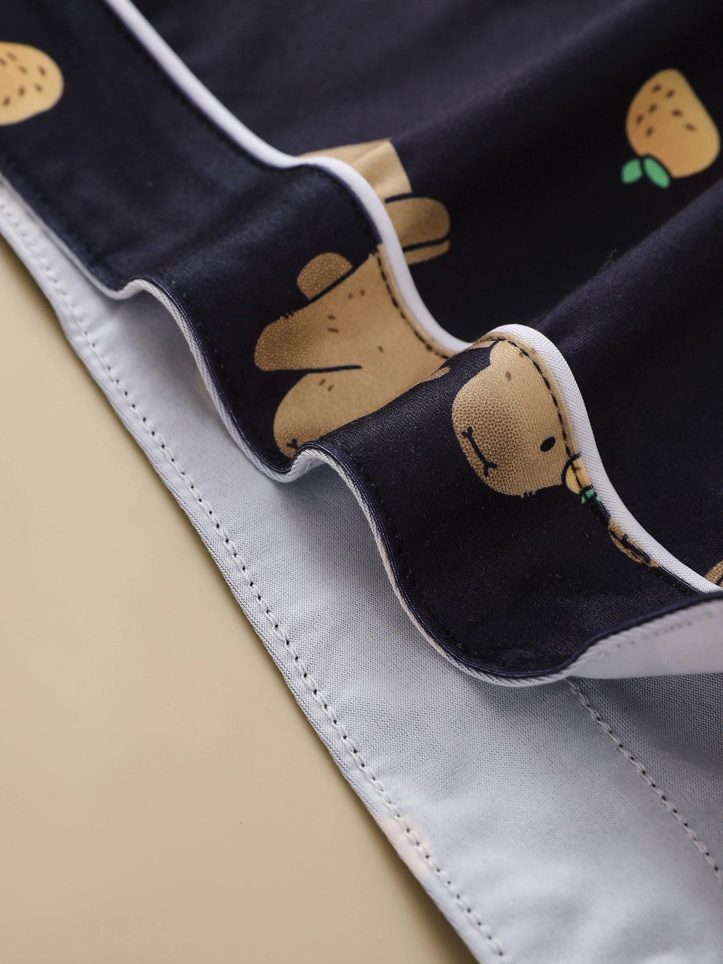 Close-up of a dark fabric with cartoon capybara design on a beige background