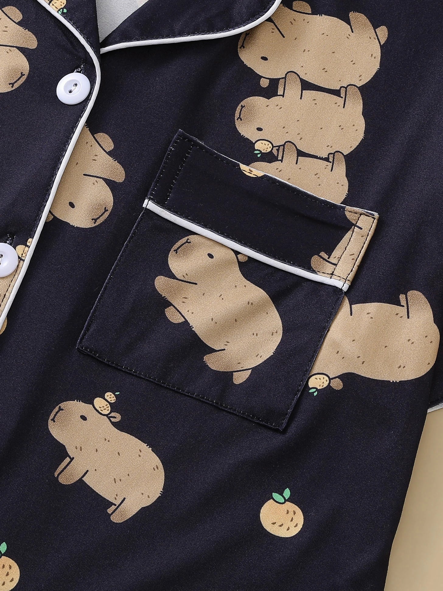 Black pajama set with beige capybara prints on a dark background