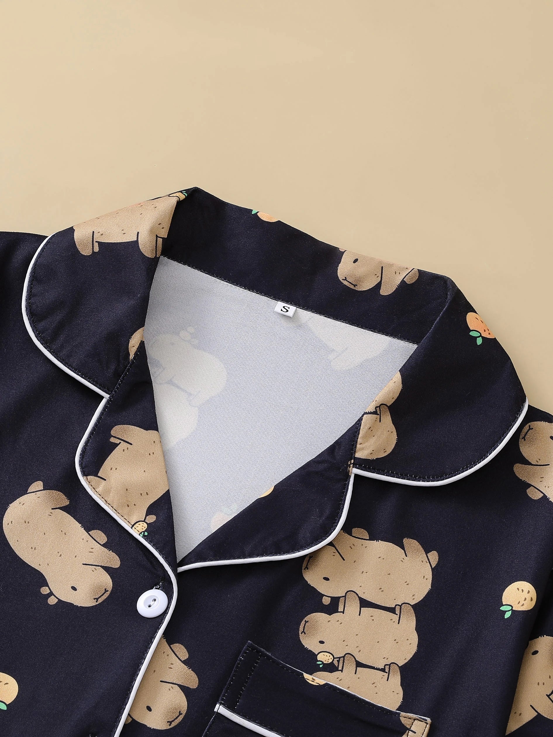 Navy blue pajama top with beige capybara patterns on a beige background