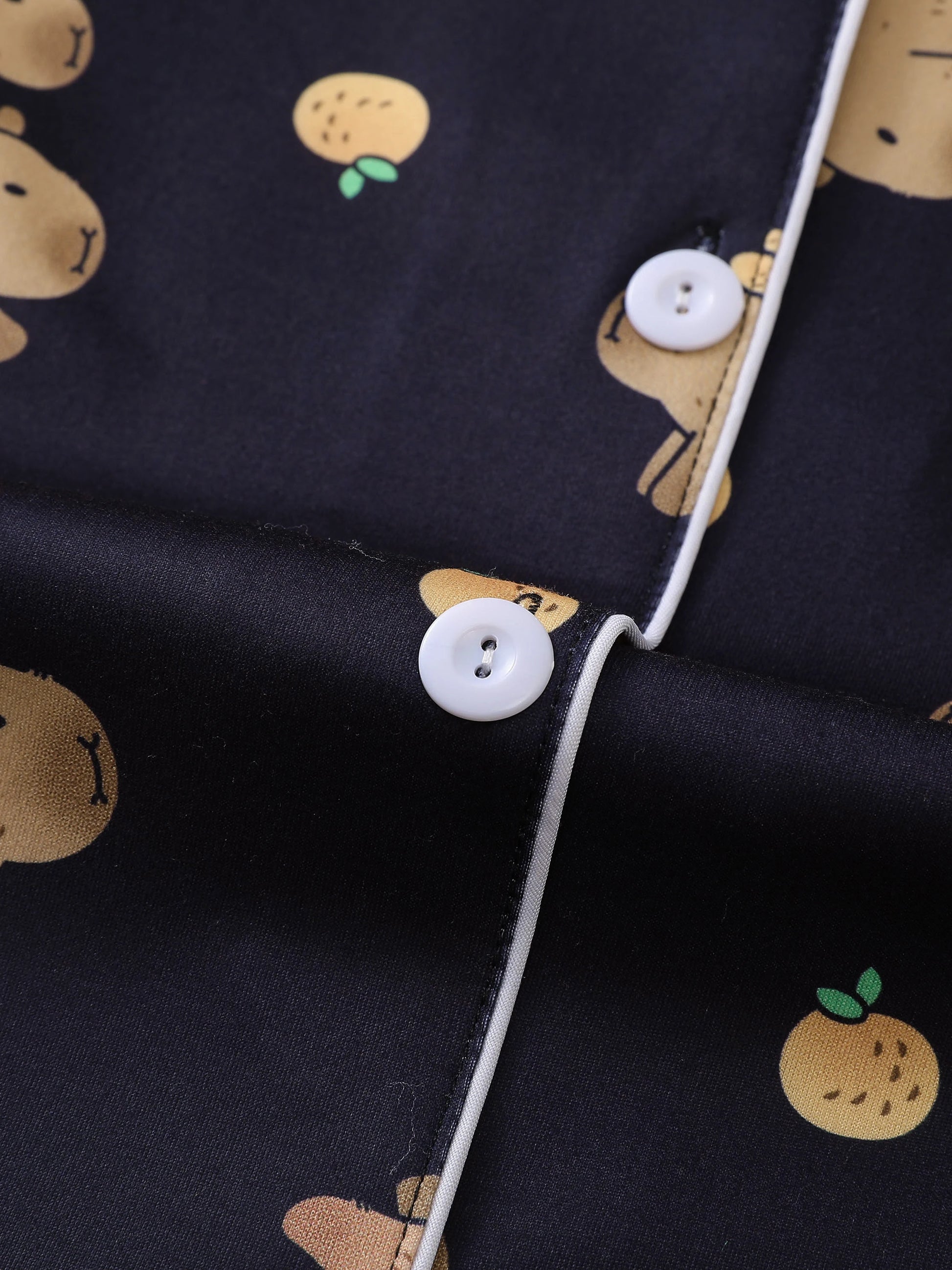 Close-up of a dark fabric with white buttons and small capybara prints.