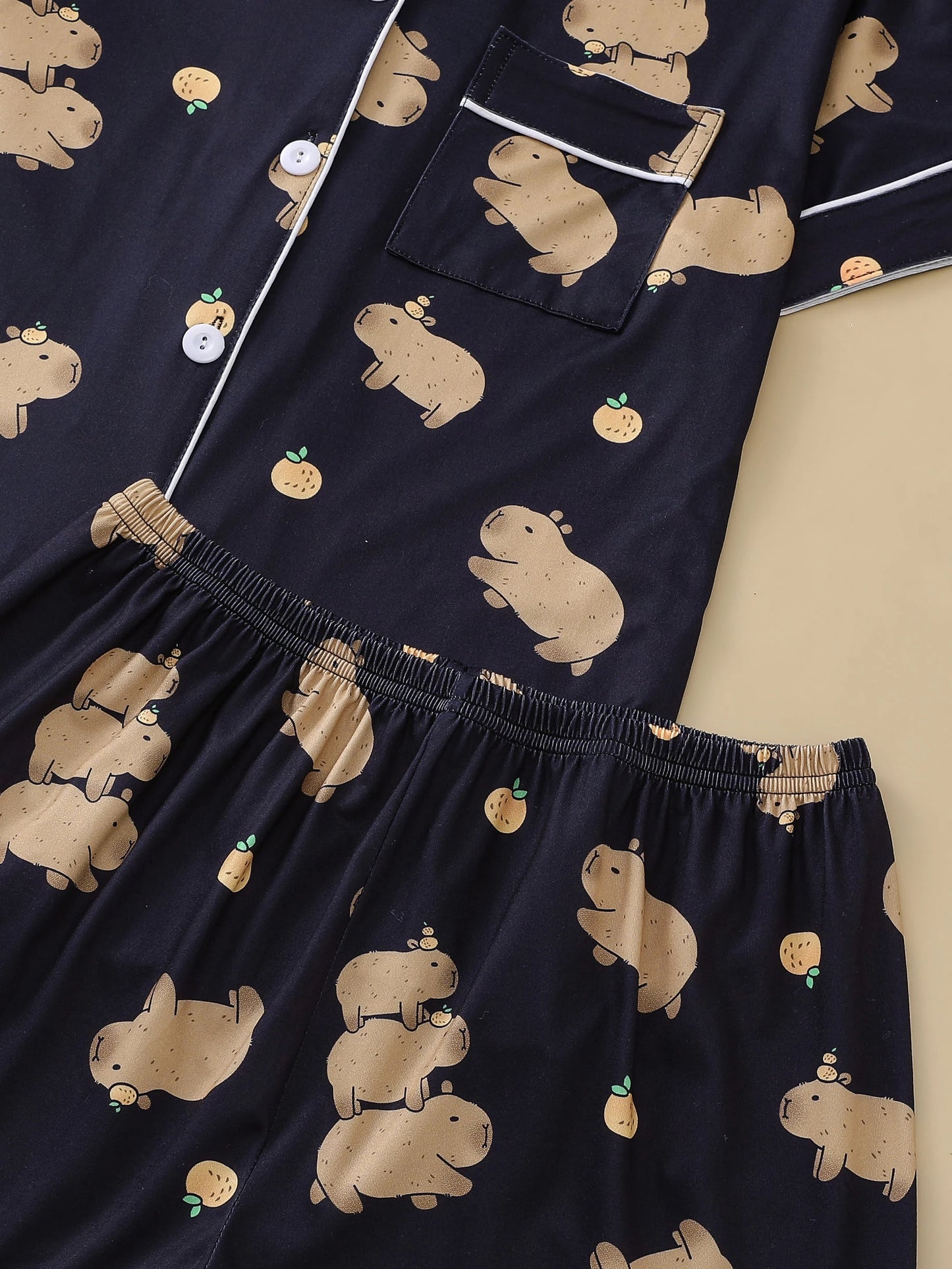 Navy blue pajama set with beige capybara prints on a beige background